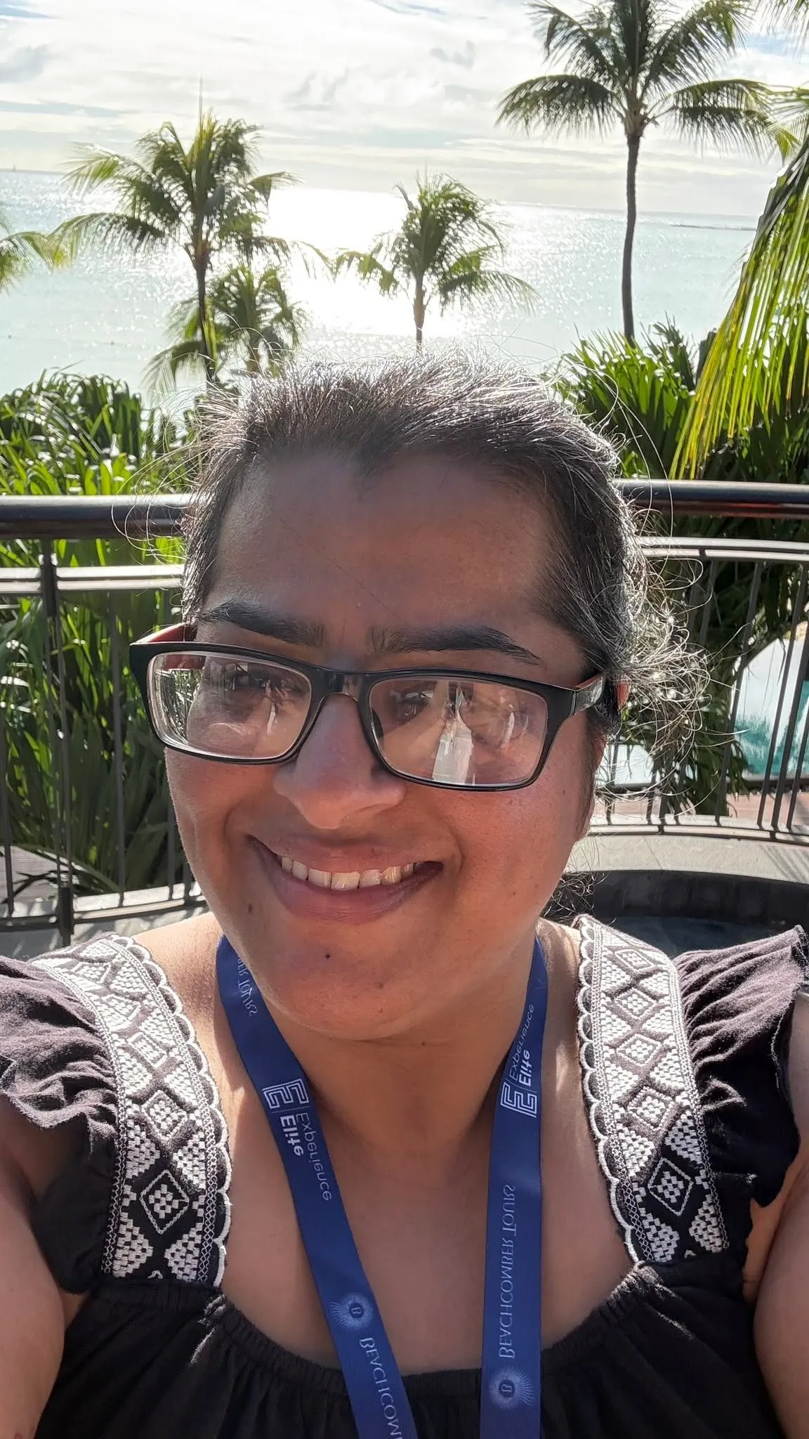 Sarita in front of a sea and palm tree backdrop