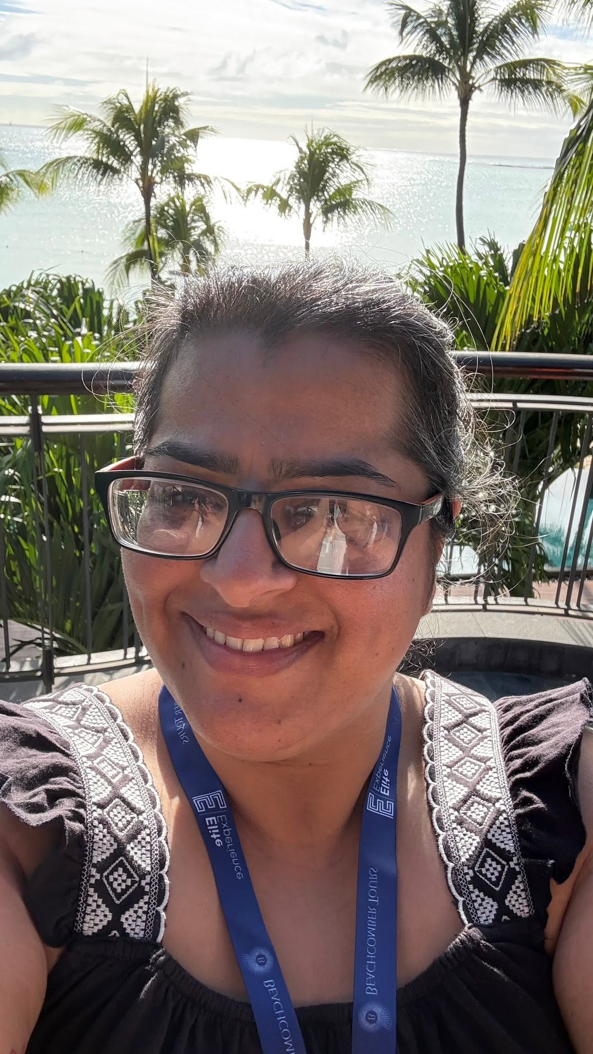Sarita in front of a sea and palm tree backdrop